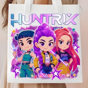 Puede incluir: Bolso tote blanco con la palabra "HUNTRIX" en azul y morado, y una ilustración de dibujos animados de tres chicas. Las chicas tienen diferentes colores de pelo y atuendos, rodeadas de estrellas moradas.