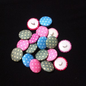 May include: A collection of 14 fabric covered buttons with white polka dots. The buttons are in various colors including pink, blue, green, and yellow.