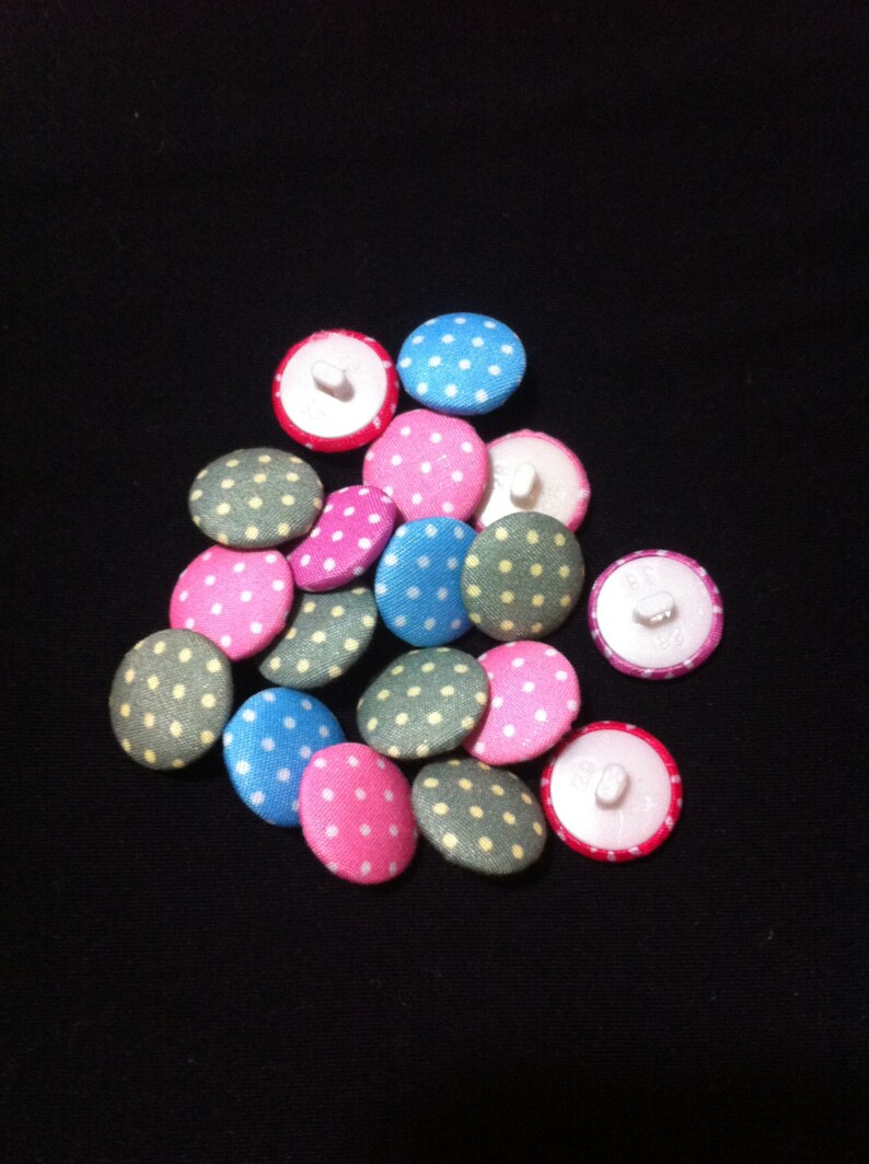 May include: A collection of 14 fabric covered buttons with white polka dots. The buttons are in various colors including pink, blue, green, and yellow.