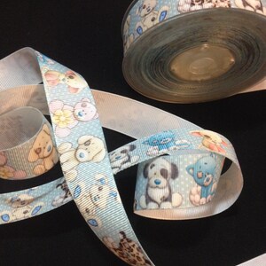 May include: A roll of blue ribbon with a white background and a repeating pattern of cartoon dogs and cats. The ribbon is on a black surface.