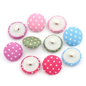 May include: Assortment of ten polka dot fabric buttons in pink, green, blue, and white. The buttons have a white plastic back with a hole for sewing.
