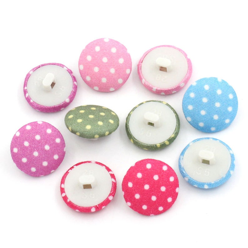 May include: Assortment of ten polka dot fabric buttons in pink, green, blue, and white. The buttons have a white plastic back with a hole for sewing.