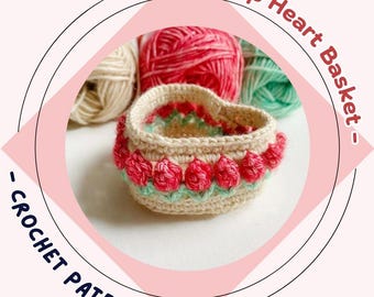 May include: A heart-shaped crochet basket with red and green tulip accents. The basket is beige with a red and green floral design around the rim. The text reads "- Tulip Heart Basket - CROCHET PATERN -."