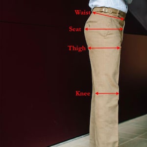 May include: Khaki-colored pants with a belt, shown with measurement labels for waist, seat, thigh, knee, and bottom. The pants are paired with brown leather shoes. The image is a side view of the pants.