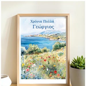 Może przedstawiać: Oprawiony wydruk akwarelowy przedstawiający krajobraz nadmorski z polem dzikich kwiatów na pierwszym planie. Grafika zawiera grecki tekst "Χρόνια Πολλά Γεώργιος" nad pejzażem morskim. Widoczna jest roślina sukulent w białej doniczce.