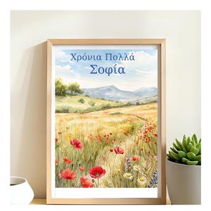 Może przedstawiać: Oprawiony wydruk akwarelowy przedstawiający pole maków i polnych kwiatów pod błękitnym niebem. Wydruk zawiera grecki tekst "Χρόνια Πολλά Σοφία" w kolorze niebieskim, osadzony na tle krajobrazu ze ścieżką prowadzącą do odległych gór. Widoczna jest roślina sukulent w doniczce.