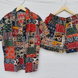 May include: A short-sleeved button-down shirt and matching shorts set featuring a vibrant patchwork design with various geometric, floral, and animal patterns in shades of red, navy blue, green, and yellow, finished with white piping trim.