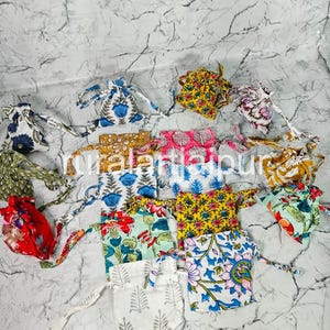 May include: A collection of small drawstring bags in various colors and floral patterns. The bags feature designs with blue, red, yellow, and green flowers and leaves. Each bag has a matching drawstring closure.