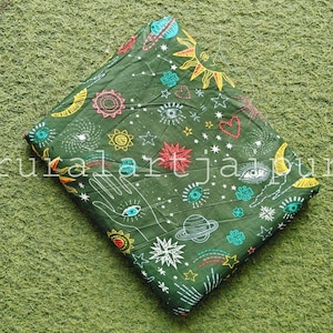 May include: A folded piece of dark green fabric featuring a repeating pattern of celestial and mystical symbols including yellow suns, white stars, planets, crescent moons, red hearts, and open hands with eyes on the palms, with the text ruralartjaipur.
