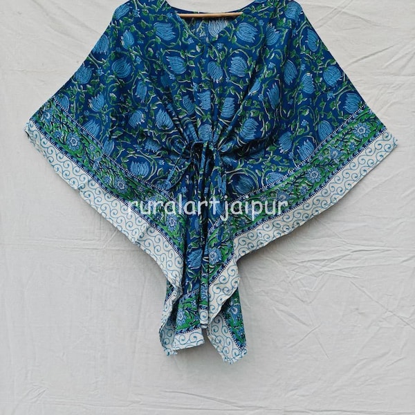 Peut inclure: Un caftan bleu orné d'un motif floral répétitif dans des tons bleu clair et vert, avec une bordure blanche à l'ourlet. Le vêtement comprend un détail de nouage central à la taille et le texte ruralartjaipur imprimé sur le devant.