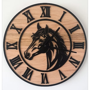 Puede incluir: Reloj de pared redondo de madera clara con un diseño de cabeza de caballo negra en el centro. La esfera tiene números romanos y manecillas negras. Un elemento decorativo para el hogar.
