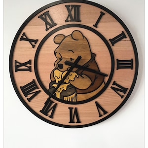 Könnte beinhalten: Wanduhr aus Holz mit Winnie Puuh. Die Uhr hat ein hellbraunes Holzgesicht mit schwarzen römischen Ziffern und einem schwarzen Außenring. Puuh wird beim Honigessen dargestellt. Die Zeiger sind schwarz.