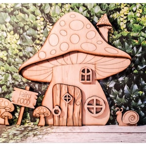 Peut inclure: Maison de fée en bois avec un toit en forme de champignon, une porte et des fenêtres. La maison porte une pancarte avec l'inscription "Fairy Food". Décorations supplémentaires en bois de champignon et d'escargot incluses.