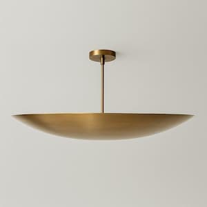 May include: A brass-coloured ceiling light. It features a circular ceiling mount, a thin rod, and a large, shallow, bowl-shaped shade. The design is minimalist and elegant, suitable for various interior styles. The shade's diameter is approximately 90 cm.