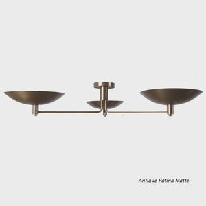 May include: An antique patina matte ceiling light fixture. The fixture has three bowl-shaped shades in a bronze finish. The text "Antique Patina Matte" is at the bottom of the image.