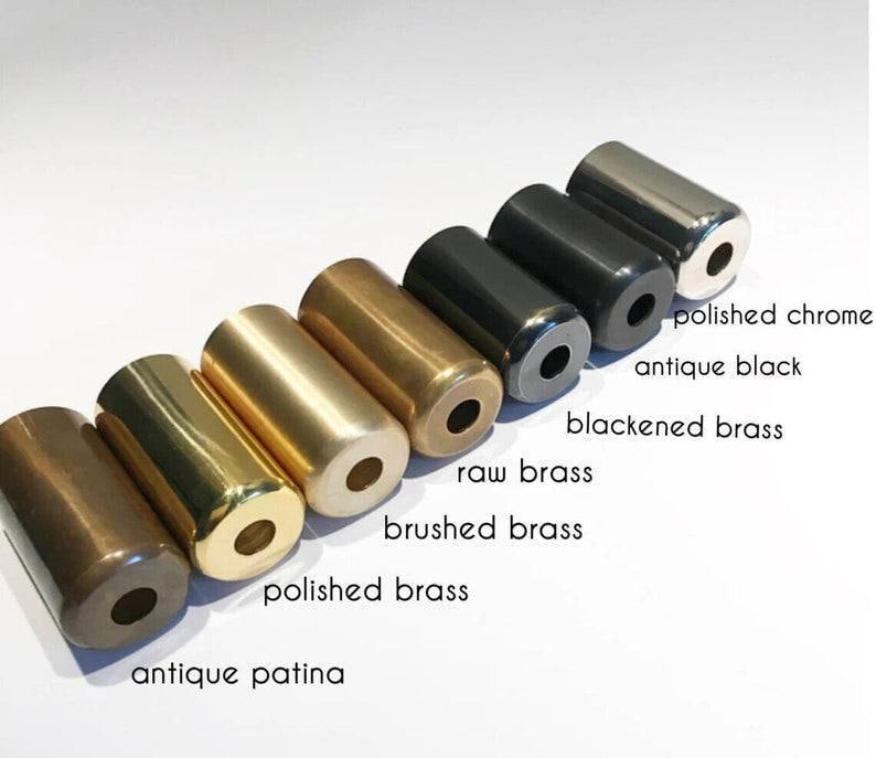 Puede incluir: Una variedad de objetos cil&iacute;ndricos de metal en varios acabados, incluyendo p&aacute;tina antigua, lat&oacute;n pulido, lat&oacute;n cepillado, lat&oacute;n crudo, lat&oacute;n ennegrecido, negro antiguo y cromo pulido. Cada uno tiene un agujero en el extremo, con etiquetas.