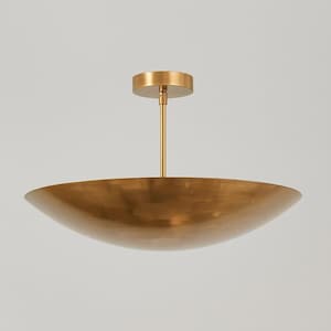 May include: A gold-colored, bowl-shaped ceiling light fixture. The fixture has a circular base and a long, slender rod connecting to a large, shallow bowl. The bowl has a smooth, reflective surface.