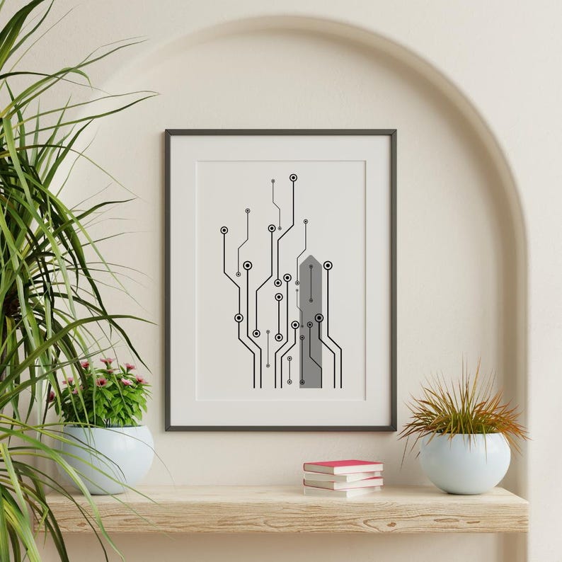 May include: Framed art print featuring a minimalist circuit board design in black and gray. The artwork is displayed in a black frame and is set against a white background. The print is displayed on a wooden shelf with decorative plants.
