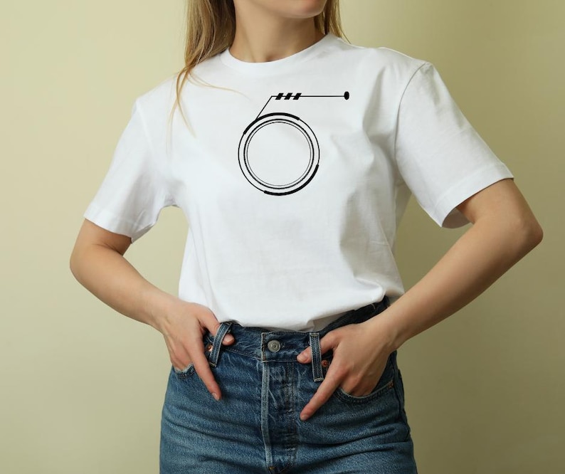 May include: White t-shirt featuring a black graphic design. The design includes a circle with a line and three short lines above it, and a dot on the right side. The shirt is made of a soft material.