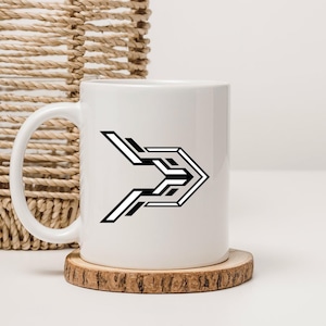 May include: White ceramic mug with a black and white geometric arrow design. The mug sits on a small, round wooden coaster. A woven basket is in the background.