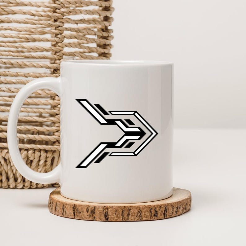 May include: White ceramic mug with a black and white geometric arrow design. The mug sits on a small, round wooden coaster. A woven basket is in the background.