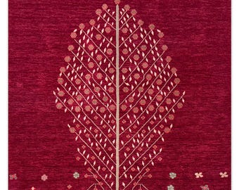 May include: A rectangular, burgundy-colored rug with a central tree design. The tree features a beige trunk and branches with small, round, floral accents in shades of pink and beige. Small floral and geometric patterns are scattered at the base.