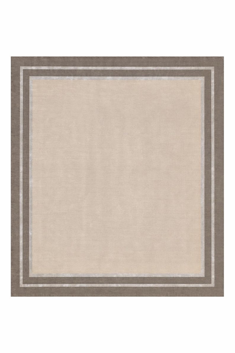 May include: A square rug with a neutral color palette. The central field is a light beige, framed by a border of darker brown and a thin silver accent. The rug's design is simple and elegant, suitable for various interior styles.