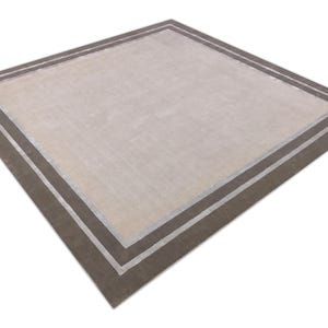May include: A square area rug with a neutral beige center and a dark brown border. The border is accented with a thin, light-colored stripe. The rug has a simple, modern design.