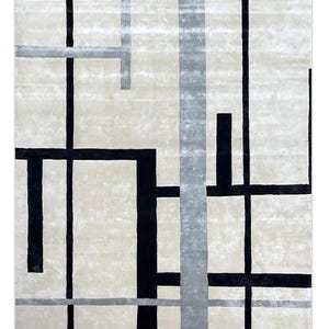 May include: A square rug with a cream-colored background and a geometric design. The design features black and gray lines of varying widths, creating a modern, abstract pattern. The rug's texture appears soft and plush.