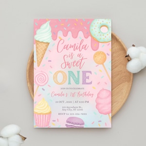 以下が含まれることがあります： パステルカラーの誕生日招待状。アイスクリーム、ドーナツ、カップケーキなどのイラストが描かれています。「Camila is a Sweet One」というテキストがあり、2025年10月23日にカミラ1歳の誕生日を祝うように招待しています。