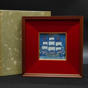 以下が含まれることがあります： 白い帆、赤い旗、青い海が描かれた、詳細な帆船が特徴の額入りの航海タイルのアート作品。 アートワークは、木製のフレーム内の赤い背景に設定され、質感のある緑色の箱が付属しています。