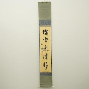 Könnte beinhalten: Eine vertikale Schriftrolle mit Kalligraphie in schwarzer Tinte auf cremefarbenem Hintergrund. Die Schriftrolle hat einen grünen oberen und unteren Abschnitt, dazwischen einen blau gemusterten Abschnitt. Die Kalligraphie enthält mehrere Zeichen und rote Siegel.
