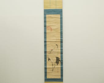 May include: A vintage Japanese scroll painting featuring cranes and a rising sun. The artwork is primarily in shades of beige, blue, and black, with a red sun. The scroll is rectangular and hangs vertically, showcasing traditional Asian art.