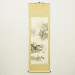 Puede incluir: Una pintura tradicional japonesa en rollo que representa un paisaje montañoso brumoso con barcos en un lago. La obra de arte presenta tonos apagados de beige, gris y negro, con caracteres japoneses en el lateral. El rollo está enmarcado con un borde estampado.