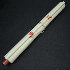 May include: A rolled-up scroll with a cream-colored paper and wooden dowels. The scroll is secured with a gold chain and sealed with red wax stamps. The background is a solid black.