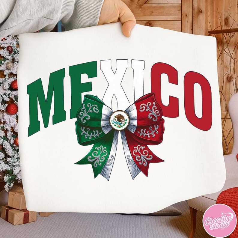 May include: White pillow with the word "MEXICO" in green and red block letters. A decorative bow in the colors of the Mexican flag is centered below the word "MEXI". The bow has green and red ribbons with ornate scrollwork.