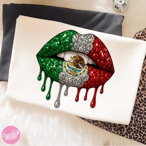 May include: White t-shirt featuring a graphic of stylized lips in the colors of the Mexican flag: green, white, and red. The lips are embellished with gems and dripping with a metallic silver and red liquid.