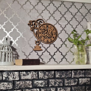 May include: A miniature decorative shelf with a wooden clock, a white birdcage, a small book, and a glass jar with greenery. The background features a gray and silver patterned wallpaper, and a brick fireplace.