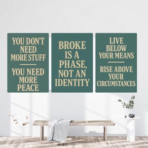 May include: Three rectangular wall art pieces with inspirational quotes in a modern font. The first reads "YOU DON'T NEED MORE STUFF YOU NEED MORE PEACE." The second says "BROKE IS A PHASE, NOT AN IDENTITY." The third says "LIVE BELOW YOUR MEANS RISE ABOVE YOUR CIRCUMSTANCES."