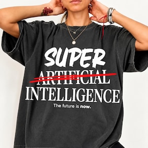Peut inclure: Un t-shirt gris anthracite à manches courtes avec le texte blanc SUPER ARTIFICIAL INTELLIGENCE, une ligne rouge barrant le mot ARTIFICIAL et le texte The future is now. imprimé en petites lettres blanches en bas.