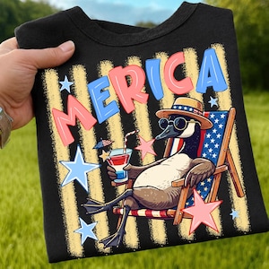 Peut inclure: Un t-shirt noir avec un motif représentant une oie portant des lunettes de soleil et un chapeau étoilé, allongée sur une chaise longue avec une boisson. Le texte 'MERICA' est imprimé en rouge et bleu, entouré d'étoiles bleu clair et roses.