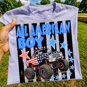 Peut inclure: Un t-shirt violet clair avec une impression graphique d'un monster truck au motif étoilé rouge, blanc et bleu. Le texte ALL AMERICAN BOY est imprimé en bleu au-dessus du camion, entouré d'étoiles bleues et rouges sur un fond à rayures noires.