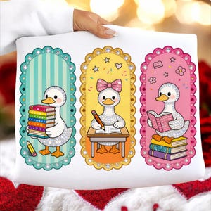Peut inclure: Coussin blanc avec trois motifs d'oies de dessin animé. Chaque oie est dans un cadre décoratif et tient des livres, un crayon ou lit. Les cadres sont turquoise, jaunes et roses avec un bord festonné et des accents de strass.