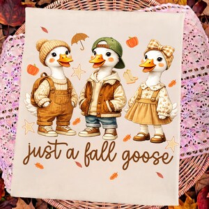 Peut inclure: Un tissu de couleur claire représentant trois oies de dessin animé vêtues de vêtements d'automne, dont un bonnet, une casquette de baseball et un nœud pour les cheveux. Le texte "just a fall goose" est imprimé sous les oies, entouré de citrouilles.