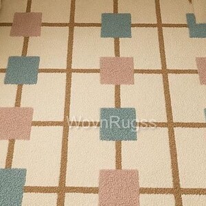 May include: A cream-colored rug with a grid pattern. The grid lines are brown, and the squares are alternating colors of dusty rose and teal. The rug has a soft, textured appearance, suitable for a living room or bedroom.