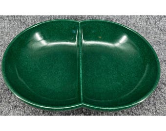 Puede incluir: Un plato de servicio ovalado de color verde oscuro con un divisor central que divide el interior en dos secciones iguales. El plato tiene un acabado liso y brillante con una textura moteada sutil en toda la superficie verde.