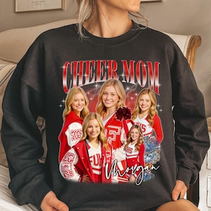 May include: Dark gray sweatshirt with a graphic that says "CHEER MOM" in red and white. The graphic features a collage of smiling cheerleaders in red and white uniforms. The name "Morgan" is written in cursive below the image.