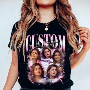 May include: Black t-shirt with a custom design featuring the word "CUSTOM" in pink, along with the text "Your Text". The design includes multiple images of a person with pink accents and a starburst effect.