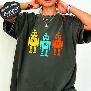 Puede incluir: Una taza de cerámica blanca con un asa negra y el texto "But First, Coffee" en negro, con una fuente de estilo manuscrito. La taza está sobre una superficie blanca.