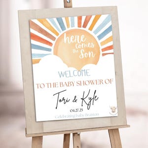 Pode incluir: Uma placa de boas-vindas para chá de bebê em um cavalete. A placa apresenta um design em aquarela com um sol e nuvens em laranja, azul e branco. O texto inclui "Here Comes the Son" e os nomes "Tori & Kyle".